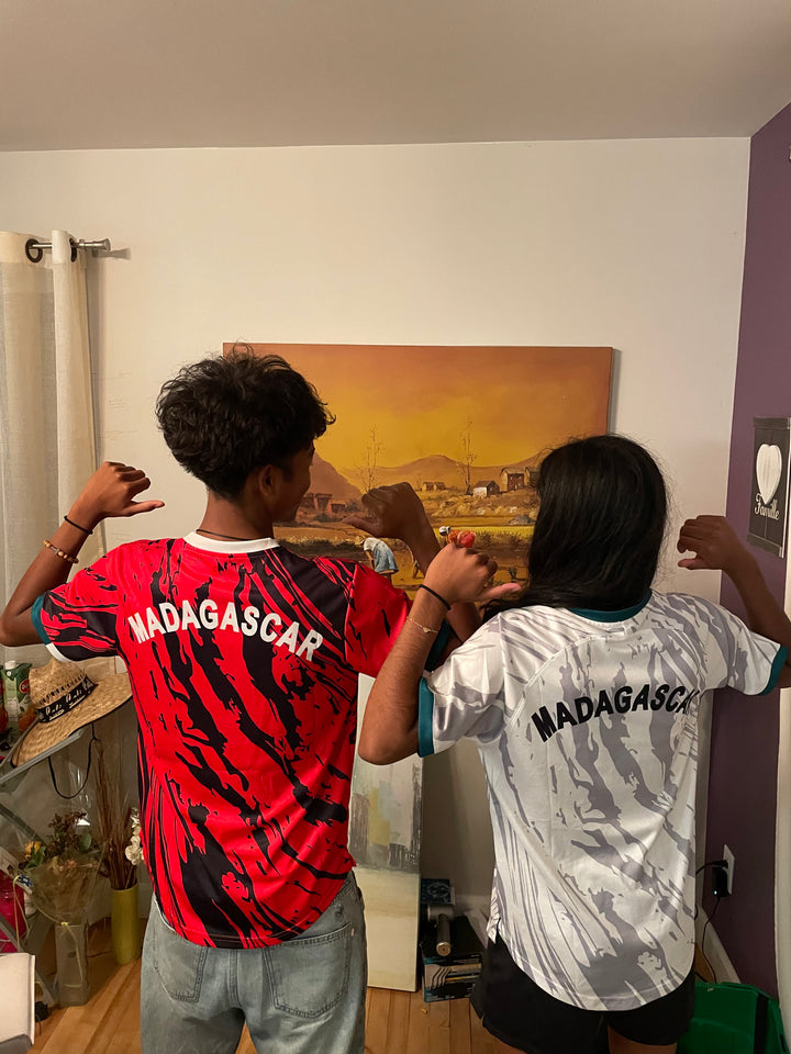 Deux clients de dos portant les maillots Madagascar rouge et blanc Barea